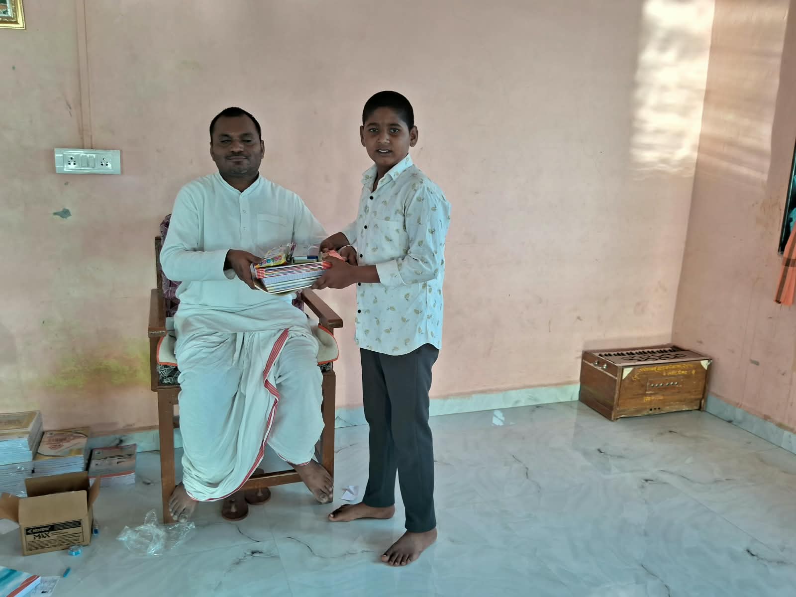 Boy receiving books from the teacher